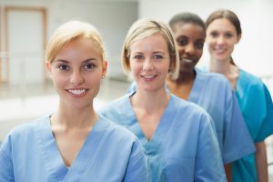 Millennial nurses stand in a line and smile.