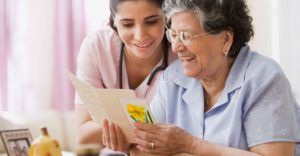 A home care nurse reads a card with a patient in her home.