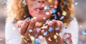 A woman blows confetti from her hands.