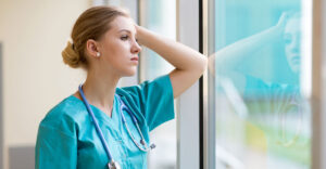 nurse looks seriously out glass window